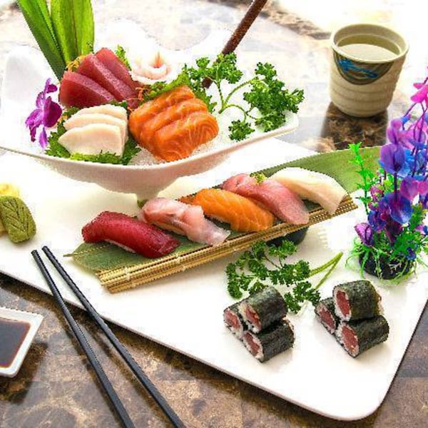 A large platter of Kabuki Japanese Cuisine's sashimi, nigiri, and sushi rolls with chopsticks and tea.